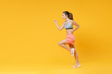Fototapeta na wymiar Full length portrait of strong young fitness woman in sportswear working out isolated on yellow background studio portrait. Workout sport motivation lifestyle concept. Mock up copy space. Running.