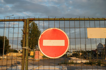 A red round road sign with a white stripe prohibiting traffic on a barred gate. Not enter. the...