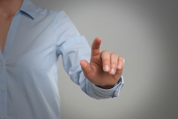 Woman touching something against grey background, focus on hand