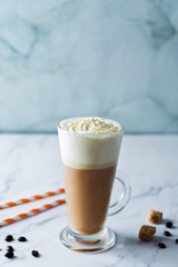 Coffee with whipped cream in a glass with coffee beans