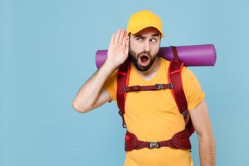 Shocked traveler man in yellow t-shirt, cap backpack isolated on blue background. Tourist traveling...