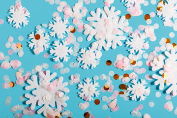 White snowflakes and confetti on a blue background. Snow and winter concept. New year and christmas concept. Beautiful winter background. Top view, flat lay.