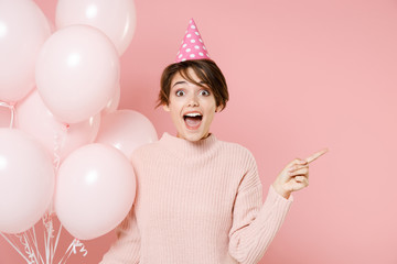 Excited young woman girl in casual sweater birthday hat isolated on pink wall background. Birthday...