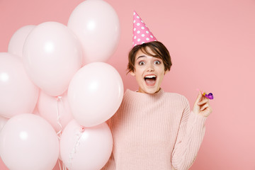Fototapeta na wymiar Excite young brunette woman girl in knitted casual sweater birthday hat isolated on pastel pink background. Birthday holiday party people emotions concept. Celebrating hold air balloons hold pipe.