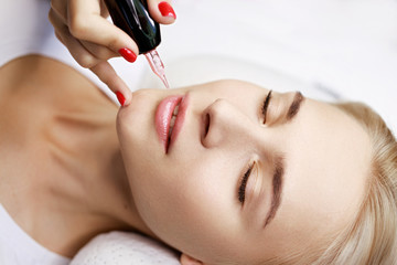 Beautiful young girl in beauty salon. Woman having permanent tattoo makeup on her lips....
