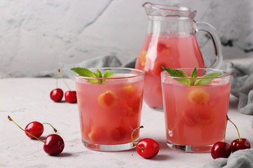 Kissel with sweet cherries in two glasses and jug on gray background, Horizontal format, Closeup