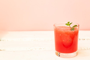 Delicious red watermelon juice with a sprig of green mint in a glass glass on a white background. Copy space. Summer food concept.