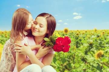 Mother and daughter with bouquet of flowers on nature background.