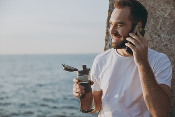 Portrait smiling young bearded fitness athletic man guy 20s in casual white t-shirt posing training...