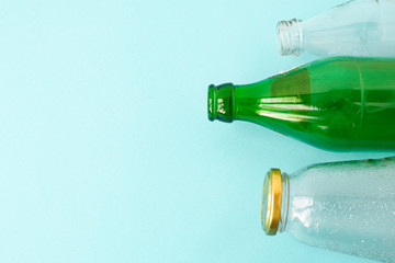 Empty glass transparent and green bottles on a blue background. A copy of the space. Ecology and Zero waste concept