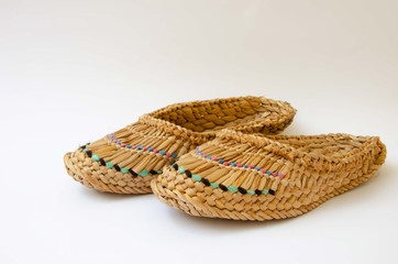 Straw slippers white background. Wicker slippers. Ancient home shoes white background.