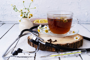 Decoction of chamomile, dried flower in flower tea and a phonendoscope, sliced lemon on a white...
