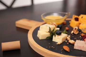 Different types of delicious cheeses, berries and nuts on table, closeup