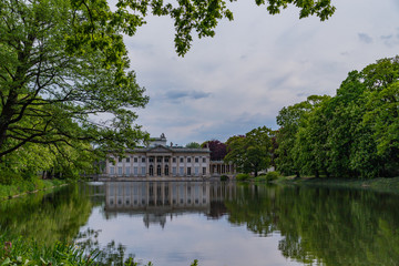Fototapeta na wymiar Palace on the Isle, Baths Palace is reflected in the water across the lake in Royal Baths Park is the largest park in Warsaw, Poland