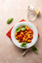 Vegan pasta with tomato sauce and basil leaves top view