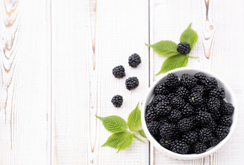 Harvest of bright, black, ripe blackberry white and brown wood backdrop. Organic and natural berries as health food concept for graphic material, wallpaper and background