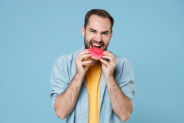 Cheerful crazy young bearded man guy 20s wearing casual clothes posing holding in hands biting...