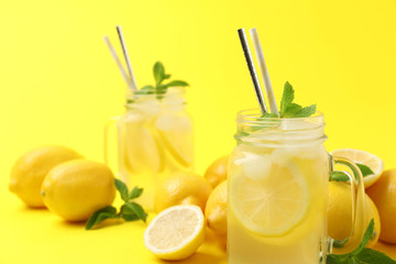 Natural freshly made lemonade with mint on yellow background, closeup. Summer refreshing drink