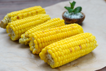 Young yellow fried sweet corn on craft paper. Delicious summer food. Close-up.