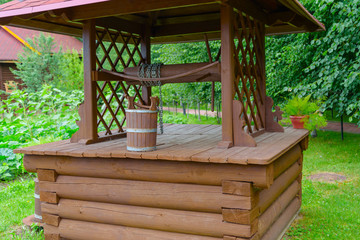 wooden well and bucket in the country side © klavdiyav
