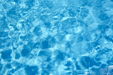 Fototapeta na wymiar Texture of blue water in swimming pool as background, closeup