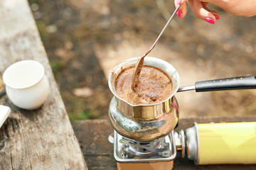 Hot drink on nature. Process of cooking coffee with spices in nature. Background - camping and forest. Active rest.