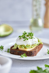 Healthy breakfast: poached egg sandwich, avocado, whole grain bread. Bruschetta on a light background. The keto diet