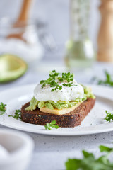 Healthy breakfast: poached egg sandwich, avocado, whole grain bread. Bruschetta on a light background. The keto diet