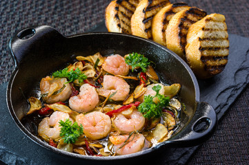gambas al ajillo, garlic prawns shrimp, spanish tapas in cast iron pan with toast