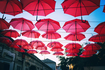 Fototapeta na wymiar Red umbrellas over street in european city, urban festive background and texture