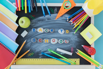 top view of school supplies lie on blackboard and stone letters  in the center of board. Back to school concept.