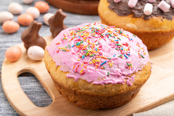 Homemade glazed and decorated easter pies on a gray wooden background and linen textile. Side view, close up.