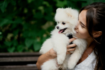 young woman holding a white puppy