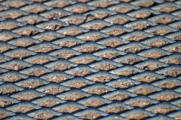 Perforated metal plate in the sand creating a texture.