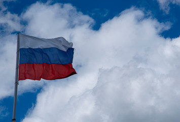 Russian tricolor flag waving in the wind against a cloudy sky.