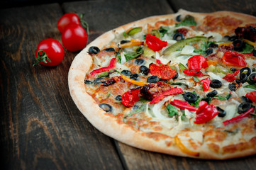 Delicious fresh pizza served on wooden table background. Summer dinner or lunch. Freshly baked Italian vegetarian pizza with vegetables. Top view.