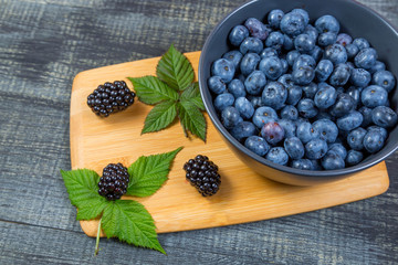 blueberry berry in dark gray ceramic bowl on dark blue wooden background.