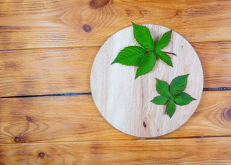 .blackberry leaves on bamboo cutting board on wooden background.