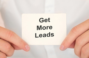Man's hands take a card with words Get more leads, finance and business concept.
