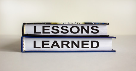 Books with text 'lessons learned' on beautiful white table. White background. Business concept.