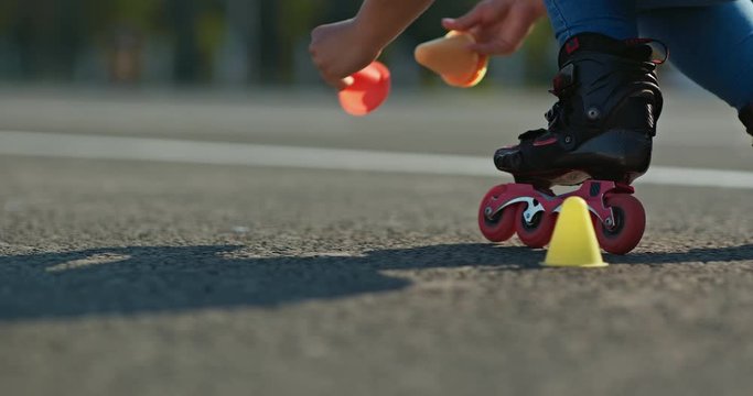 Roller skating on asphalt and placing cones, marking the track. Roller sport trainer, roller skates ride on the road, close-up. 4k, 10bit, ProRes