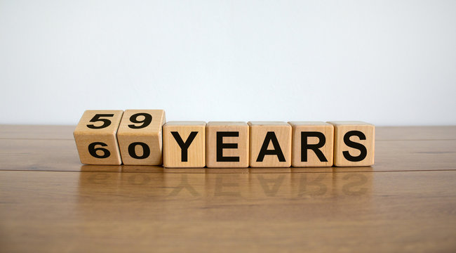 Turned cubes and changed the expression '59 years' to '60 years' or vice versa. Beautiful wooden table, white background. Business concept, copy space.