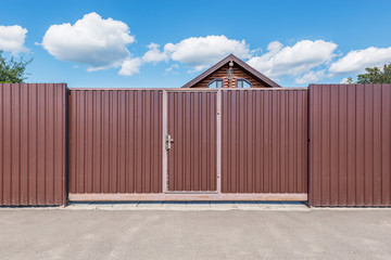 Fototapeta premium Metallic new gate by the house at summer time.