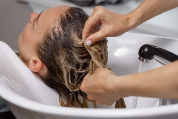 Obraz na płótnie Canvas hairdresser washes hair of a young woman before a haircut