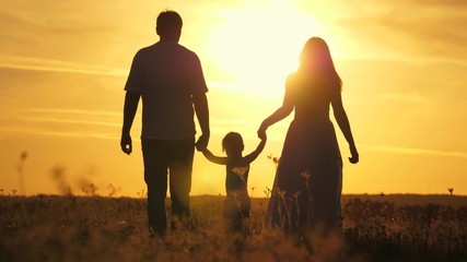 mom, dad and baby play outdoors. healthy little daughter jumps and flies in arms of mother and father in field at sunset. Happy family walks in field in sun. concept of happy family of children.