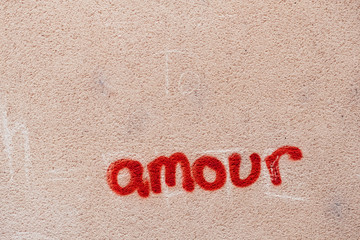 Mot amour écrit en rouge sur un fond en béton rose