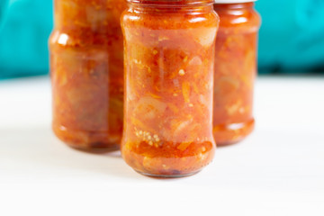 fermented tomato, paprika, aubergine sauce in glass jars on  white wooden background