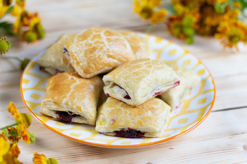 Just from oven baked pastry with jam on plate on white wooden table with fresh flowers