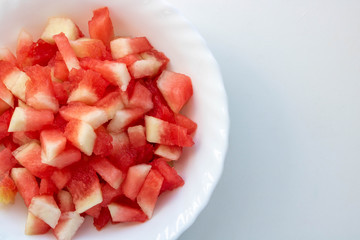 Pieces of watermelon in a white plate on a white background.Space for your text