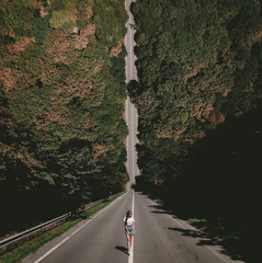 A young lady standing on a countryside asphalt road. Photo in the style of the film Inception....
